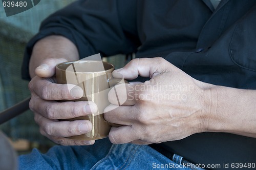 Image of Man holding a hot drink in a mug