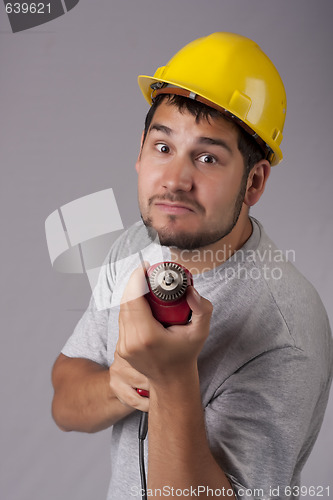 Image of Freakish worker with yellow protective helmet and drill