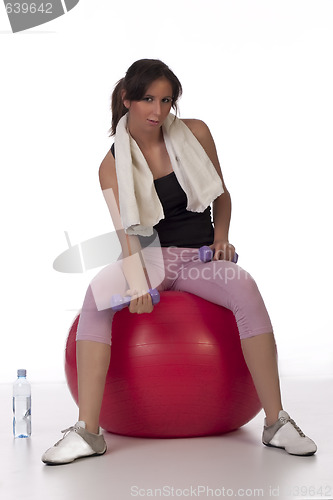 Image of Woman on white holding purple dumbbells on a ball