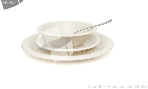 Image of Beige soup, dinner plates and saucer with spoon isolated