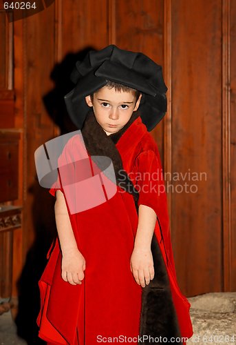 Image of Serious cute little boy in medieval costume standing on wooden background