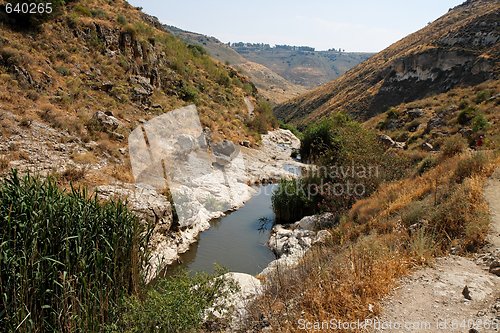 Image of Narrow stream flows in stone banks