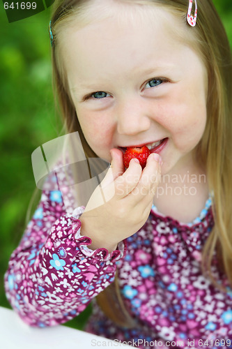 Image of Smiling little girl eating a strawberry. 