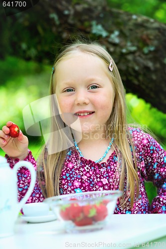 Image of Smiling little girl holding a strawberry at tea party.