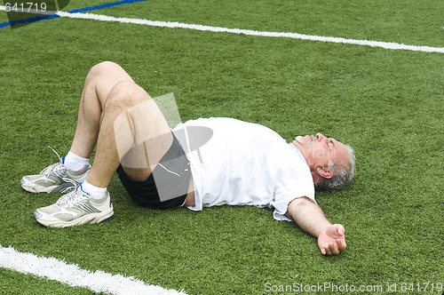 Image of middle age man stretching and exercising on sports field