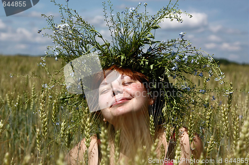 Image of The smiling girl in a garland among the ears of the wheat