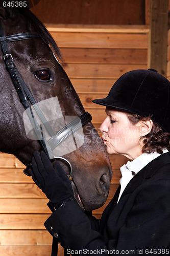 Image of Senior woman kissing her horse