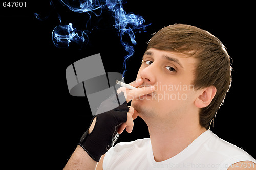 Image of Young man smoking a cigarette. Isolated on black