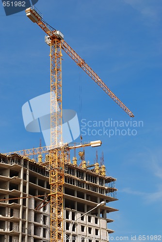 Image of yellow tower crane building a multistory