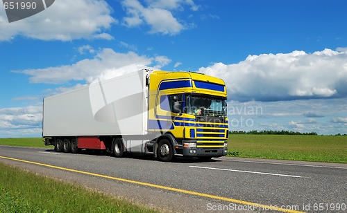 Image of Single truck with blue-yellow cabin moving on highway.