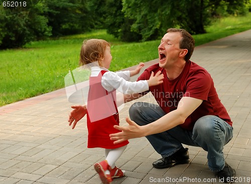 Image of Laughing man (father) playing with little girl (daughter)