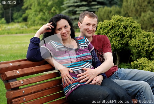 Image of Young happy couple (pregnant woman) on bench