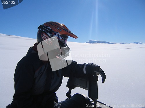 Image of Man with helmet on snow scooter