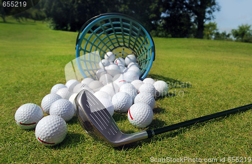 Image of Golf balls pouring out of basket onto grass