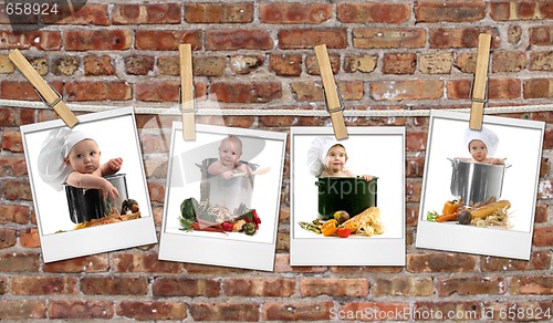 Image of Baby Chefs in Pots Hanging on Film Blanks Against Brick