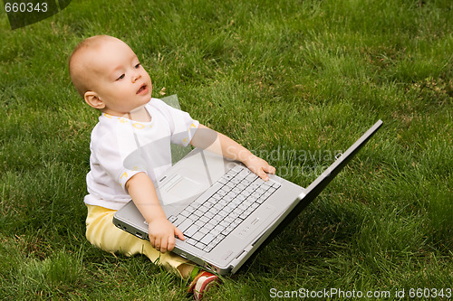 Image of Little child playing with notebook on the grass