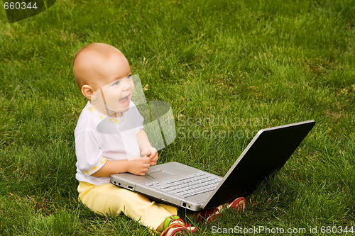 Image of Little child playing with notebook on the grass