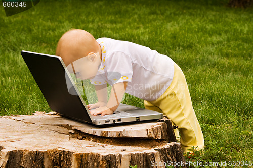 Image of Little child playing with notebook on the grass