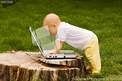 Image of Little child playing with notebook on the grass