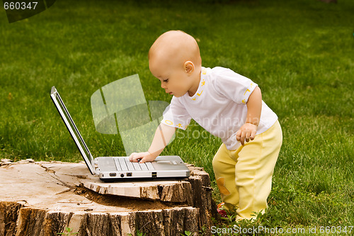 Image of Little child playing with notebook on the grass