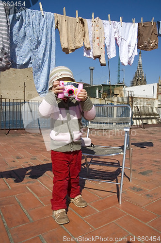 Image of sweet girl with pink digital camera and clothesline