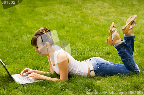 Image of Happy young woman with notebook on the grass