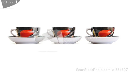 Image of Row of three black tea cups with saucers isolated 