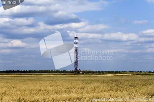 Image of communications tower on field with cloudy sky background