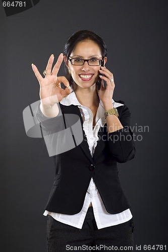 Image of picture of an attractive businesswoman on the phone winning and making her ok sign