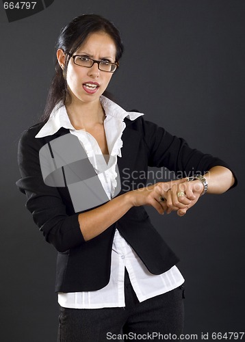 Image of attractive businesswoman checking time over black background