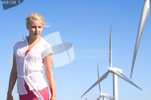 Image of young woman dreams about the future on a wind farm beneath eolic