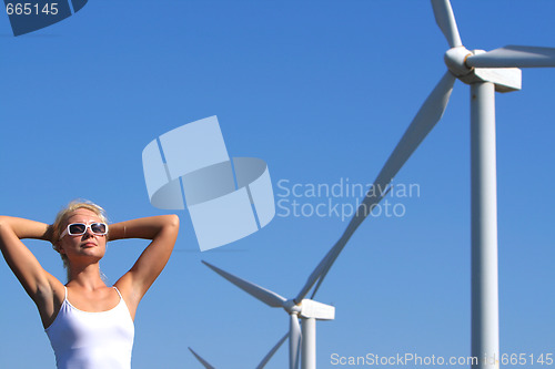 Image of young woman dreams about the future on a wind farm beneath eolic