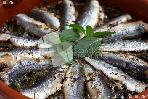 Image of Sardines baked in a terracotta bowl