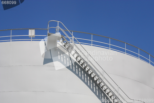 Image of  Oil reservoir detail with access ladder against a blue sky