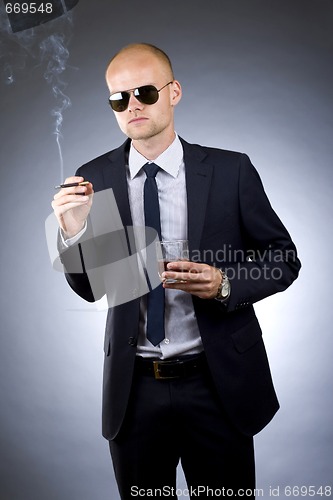 Image of young businessman drinking and smoking