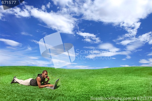 Image of Student Working on a Computer Outdoors in a Beautiful Field of G