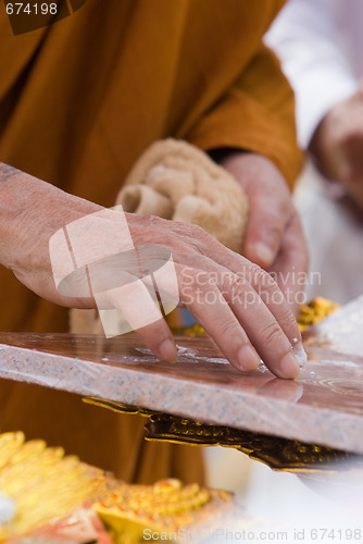 Image of Hand of Buddhist monk painting religious symbols
