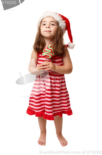 Image of Little girl wearing santa hat and holding Christmas candy