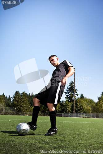Image of Hispanic soccer or football player kicking a ball