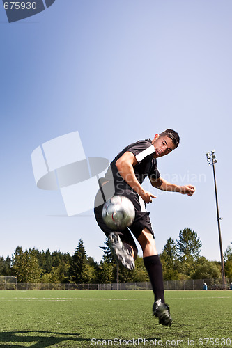 Image of Hispanic soccer or football player kicking a ball