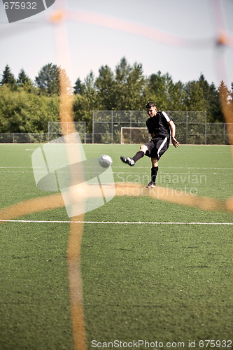 Image of Hispanic soccer or football player kicking a ball