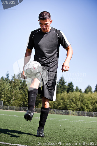 Image of Hispanic soccer or football player kicking a ball