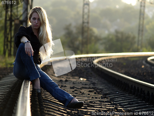 Image of Young woman sitting on rail