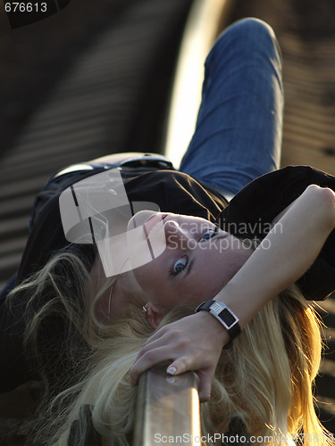 Image of Young woman lying on rail