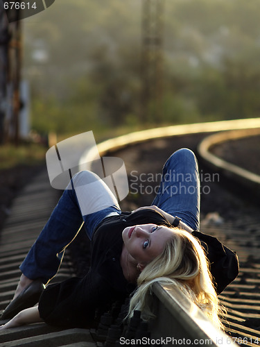 Image of Young woman lying on rail