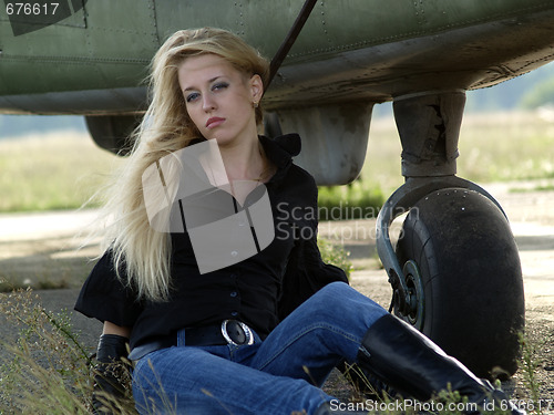 Image of Young woman sitting near airplane