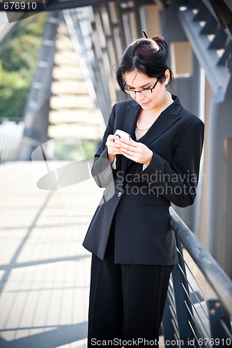 Image of Hispanic businesswoman texting 