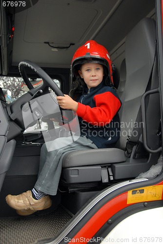 Image of boy is sitting in a fire truck