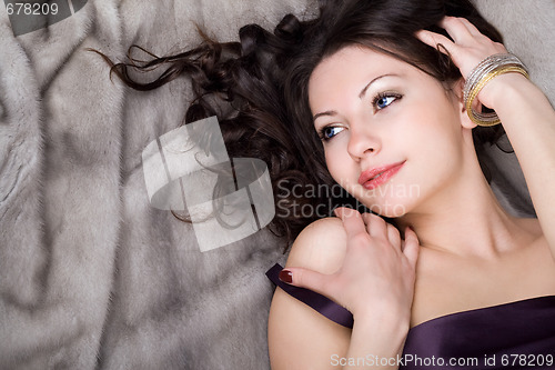 Image of Sexy girl lying on grey fur coat