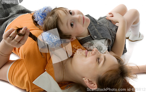 Image of smiling mother and daughter lie on  floor